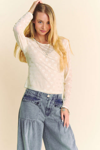 Cream Bows Long Sleeve Layer Top on a hanger, showcasing delicate bow details and soft fabric for a stylish look.