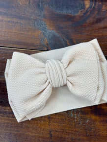 Cream oversized headband bow for baby girls, showcasing soft, comfortable material in a chic, stylish design. Perfect for any outfit.