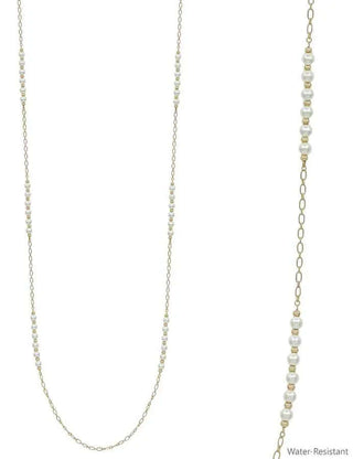 Elegant long gold necklace featuring lustrous pearls and shimmering gold bead accents on a chic velvet display.