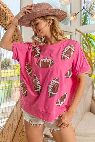 Bright hot pink top with sequined football patches, perfect for game day fashion and fan spirit. Ideal for stylish sports lovers.