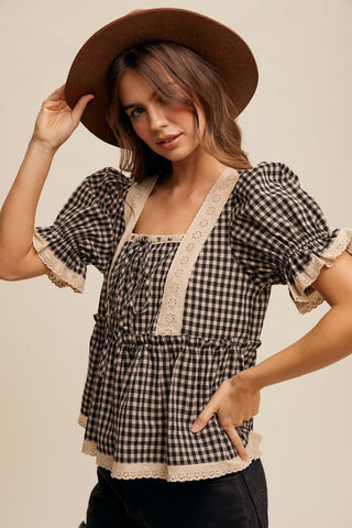 Woman wearing a checkered blouse with lace trim and a brown hat against a beige background