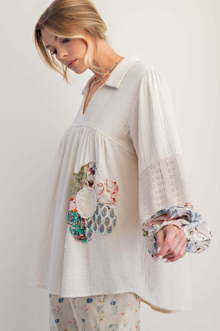 Easel ecru tunic top with patchwork flower mixed fabric sleeves displayed on a hanger against a white background.