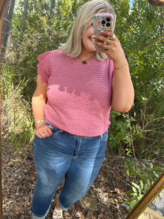 Pink textured short-sleeve knit top with ruffle details and crew neckline.
