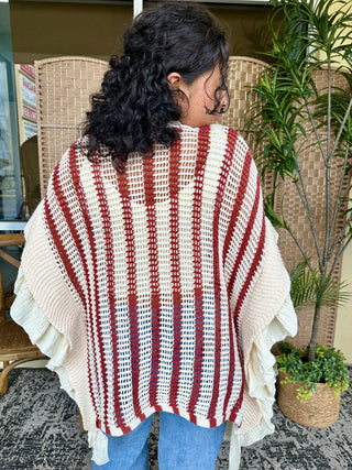 Red and white striped knit poncho with textured openwork pattern and ruffled cream edges.
