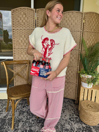 Cream short-sleeve sweater with red lobster graphic and contrast trim, paired with red and white striped pants.
