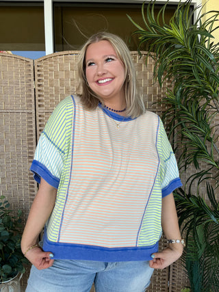 Oversized dolman top with yellow, orange and white horizontal stripes, blue trim and crew neckline.
