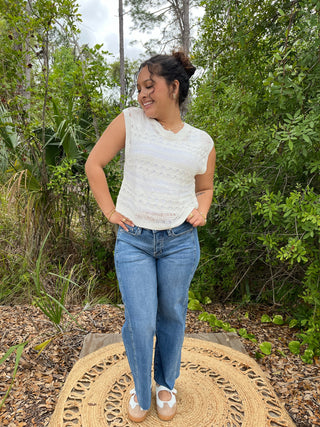 Cream crochet sleeveless top with textured knit pattern paired with blue jeans.
