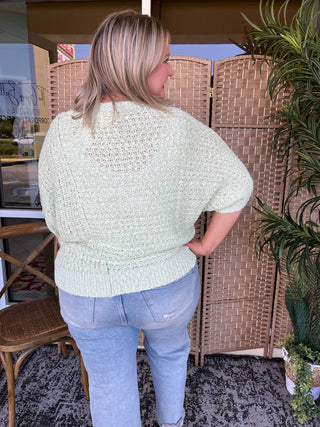 Cream textured knit sweater with asymmetrical puff sleeves and waffle-knit ribbed hem.
