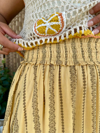 Yellow maxi skirt with brown vertical striped pattern and crochet lemon appliqué detail at waistband.

