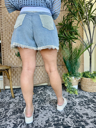 Light blue striped denim shorts with white lace trim and distressed edges, back view.
