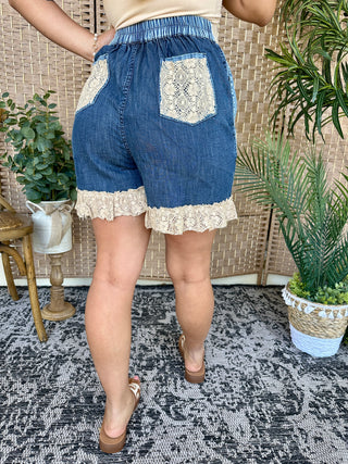 Blue denim shorts with cream lace pockets and hem trim, elastic waistband.
