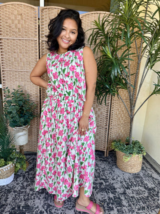 Sleeveless floral dress in pink and white with green leaves, cinched waist, full skirt.
