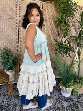 Light blue and cream ruffled sleeveless dress with tiered hemline and daisy embroidery detail.
