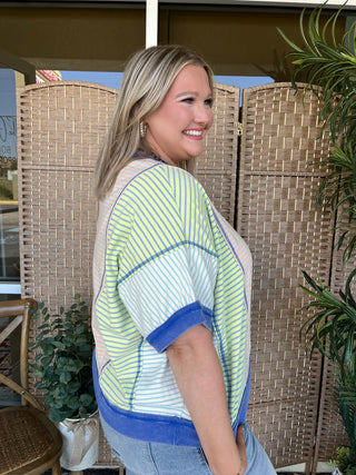 Lime and white striped dolman top with blue trim and contrasting geometric pattern details.

