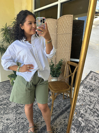 White pinstripe button-up shirt with puffed sleeves paired with sage green shorts.
