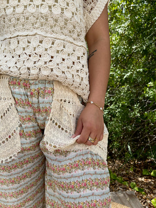 Cream crochet lace top with floral patterned pants and decorative trim details.
