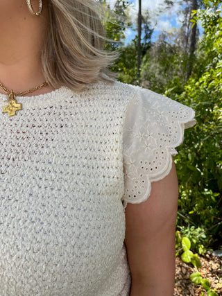 Cream textured short-sleeve top with scalloped eyelet lace trim on sleeves.
