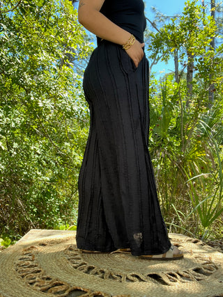 Black textured wide-leg pants with side pockets and relaxed fit.
