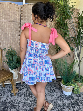 Blue and red sardine print short dress with pink tie-shoulder straps and ruched bodice.
