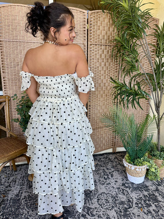 White off-shoulder ruffle dress with black polka dots and tiered layers.
