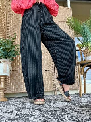 Black pinstripe relaxed fit pants paired with hot pink knit sweater and tan slides.
