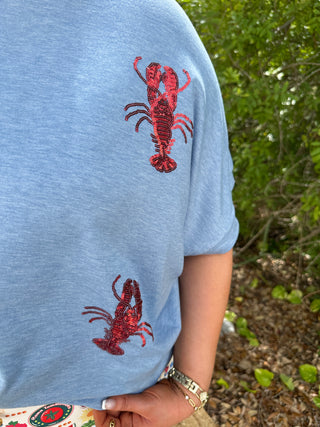 Light blue t-shirt with red sequin lobster graphic on chest and sleeve.
