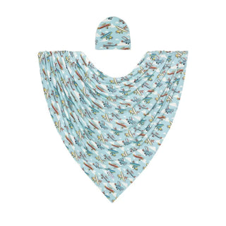 Infant wrapped in Posh Peanut's Bamboo Swaddle with Beanie, featuring plane designs, cozy and stylish for all-season comfort.