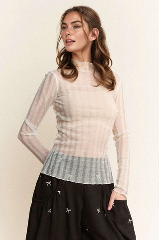 White round neck long sleeve top with dainty dot pattern, perfect for layering, displayed on a hanger against a neutral background.