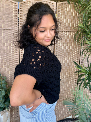 Black open weave short-sleeve sweater top with textured knit pattern and ribbed trim.
