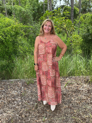 Polagram Dress Terracotta Dream Floral Patchwork Maxi featuring vibrant colors and elegant design on a mannequin in a garden setting.