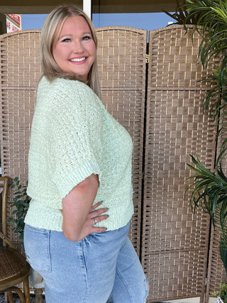 Mint green asymmetrical knit sweater top with textured fabric and short sleeves.
