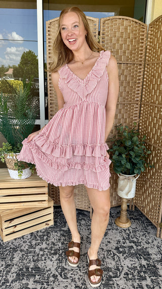 Pink and white striped sleeveless dress with ruffled V-neckline and tiered ruffle hem.
