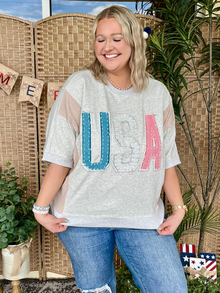 Heather gray oversized tee with blue and pink USA graphic and pearl embellishments.
