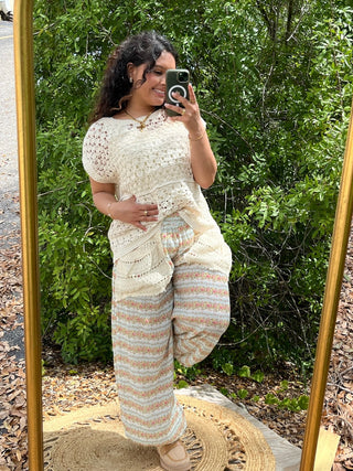 Cream crochet short-sleeve top with multicolor striped knit pants in aqua and peach tones.
