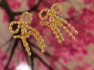 Gold beaded bow drop earrings with cascading beaded fringe details against blurred pink floral background.
