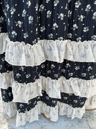 Navy floral maxi skirt with ivory ruffles, featuring a flowing design and vibrant flower patterns.