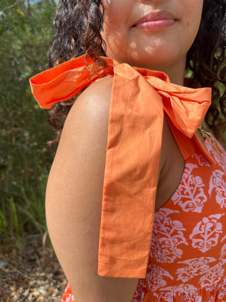 Orange damask print maxi dress with peach bow shoulder detail.
