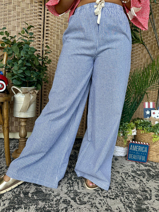 Blue and white striped wide-leg pants with elastic waist, displayed on model with casual styling.
