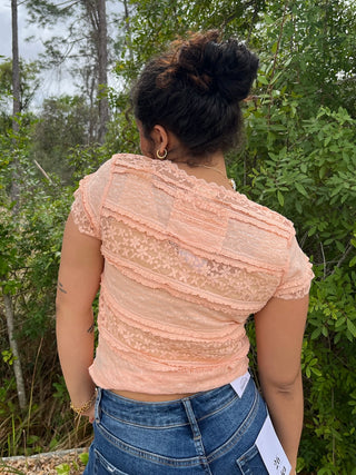 Peach lace short-sleeve top with textured layered pattern and ruched details.
