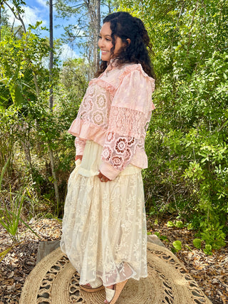 Blush pink lace shacket with floral cutout detail over cream embroidered maxi skirt.
