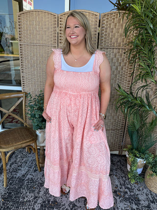 Pink eyelet sleeveless jumpsuit with ruched bodice and wide-leg pants, white trim neckline.
