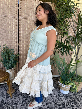 Light blue sleeveless tunic with embroidered daisy, tiered white ruffle skirt overlay.
