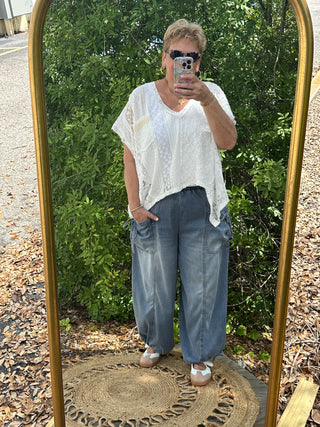 White lace short-sleeve handkerchief top with asymmetrical hemline paired with medium wash jeans.
