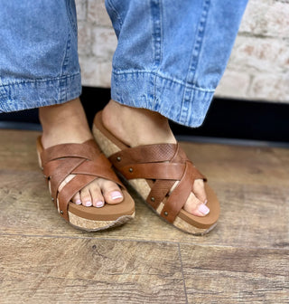 Brown leather strappy platform sandal with cork sole worn with light blue jeans.
