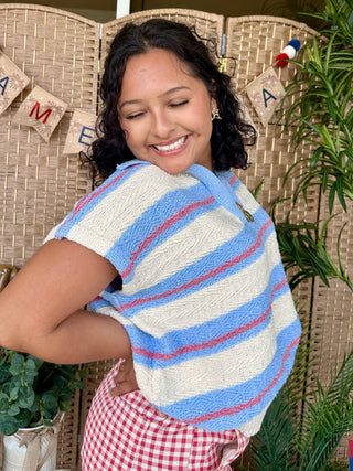Periwinkle blue, cream, and red striped knit sweater with short sleeves and textured fabric detail.
