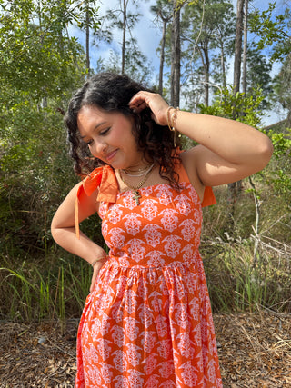 Orange damask print sleeveless maxi dress with ruffled neckline and fitted bodice.

