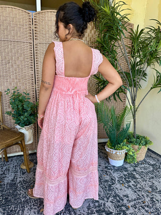Pink eyelet jumpsuit with open back and ruffled straps, shown from behind.
