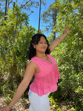 Pink textured V-neck sleeveless top with ruched layered fabric detail and asymmetrical hem.
