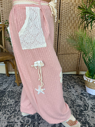 Blush pink ribbed joggers with white lace pocket detail and cream rope drawstring with starfish charm.
