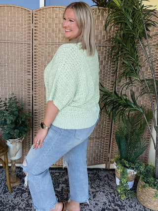 Mint green textured knit sweater with asymmetrical hem and three-quarter sleeves.
